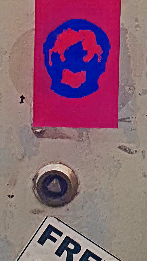 A vibrant sticker featuring a skull design. The skull is depicted in blue with red accents, set against a bright red background. It's pasted on a weathered surface alongside other markings.