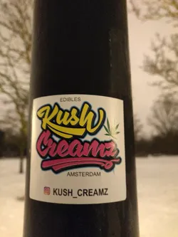 Street sticker A sticker featuring the Kush Creamz brand logo. The logo is stylized text with a cannabis leaf. The sticker also includes the city name Amsterdam and a social media handle.