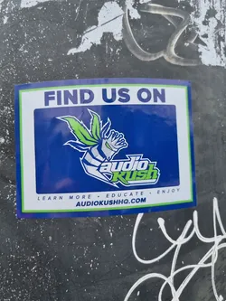 Street sticker Sticker featuring the Audio Kush logo. The logo has a cartoonish figure with marijuana leaves, and the text 'Audio Kush' is written in a stylized font. The sticker also has a website address. 