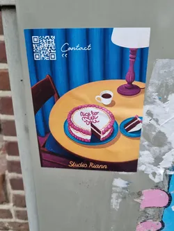 Street sticker A charming sticker featuring a heart-shaped cake with the words "Nice to meet you" on it. The sticker also includes a QR code for contact, a table setting with a coffee cup, and a lamp.  The artist's signature, "Studio Riann", is visible at the bottom.