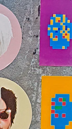 This sticker features a pixelated monster design in blue, yellow and red hues on a magenta square background.