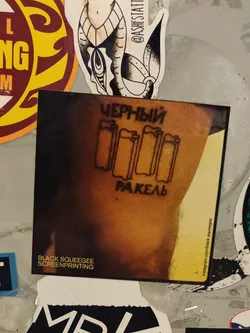 Street sticker A sticker featuring an image of a person's arm with a screenprinted design. The design consists of four stylized squeegees and text in Cyrillic that translates to "Black Squeegee". The sticker also includes the text "BLACK SQUEEGEE SCREENPRINTING" and a social media link to Instagram.