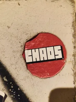 Red circle sticker with the word CHAOS in a bold, sans-serif font. The sticker is slightly peeling at the edges.