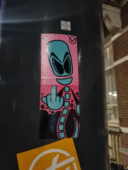A sticker featuring a cartoon alien with a spine giving the middle finger.  The alien is teal and pink, set against a black background with pink and black bubbles. 