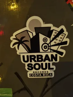 Street sticker A sticker featuring the logo for Urban Soul Records, located in Costa Rica. The logo depicts a stylized cityscape with palm trees, a speaker, and radiating sound waves.  The text 'Urban Soul' is prominently displayed, with 'Records' and 'Costa Rica' in smaller text below.