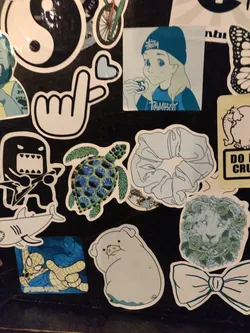 Street sticker Collection of stickers in varying light blue shades.  The central sticker shows a stylized cartoon girl with light blonde hair wearing a blue beanie.  Other stickers include a sea turtle with a detailed shell, a hair scrunchie, a simple pig illustration, and a lion's face surrounded by leafy elements. All stickers share a consistent light blue color palette.