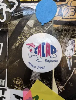 Street sticker A round white sticker with a cartoon drawing of a tortoise wearing a red beret. The words 'CALAO Bayonne' are written above the tortoise and 'depuis 1982' underneath.  The style is simple and graphic.