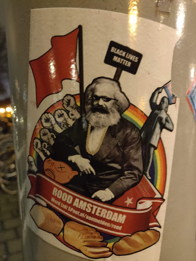 Street sticker This sticker features Karl Marx in the center, with raised fists, a red flag, a Black Lives Matter sign, and a rainbow in the background.  There are loaves of bread at the bottom.  The text at the bottom says "ROOD AMSTERDAM" and includes a URL.