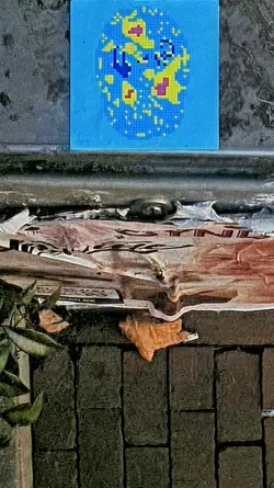 Street sticker A square sticker featuring a pixelated globe with blue as the dominant color. The globe has yellow and purple landmasses. The style is reminiscent of early computer graphics, and it's affixed to an old brick surface.