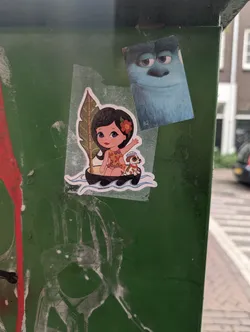 Street sticker The sticker features a stylized illustration of a young girl with dark hair and a flower behind her ear, wearing a vibrant, cut-out swimsuit. She is seated in a small, dark boat, accompanied by a small dog wearing a sailor's hat. Behind the girl is a large, green tropical leaf. The boat is depicted floating on blue, wavy water. The overall style is cartoony and playful, with bright colors.