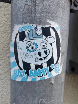 Street sticker A sticker featuring a cartoon pig wearing a miner's helmet. The pig has a bandage over its eye and its tongue is sticking out. The sticker has a black and white striped background with blue accents. The text "110% ANTI*O" is visible at the bottom.