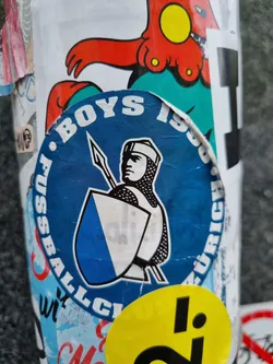 A round sticker featuring the logo of FC Boys Zürich 1900. The logo depicts a knight holding a spear and shield with the club's colors.  The text "BOYS Fussball Club ZURICH" circles the main image.