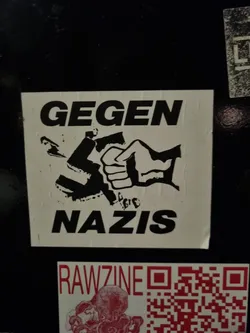 Street sticker A sticker depicting a fist smashing a swastika. The text 'GEGEN NAZIS' is written above and below the image.  The sticker expresses anti-Nazi sentiment.