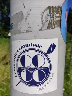 Street sticker A sticker featuring the logo of Asopos de Vliet, a rowing club. The logo is a circular design with the letters 'CC' intertwined, with a depiction of rowing boats below.  The text 'Commissie' is written around the top of the circle and 'Asopos de Vliet' is written at the bottom.