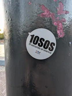Street sticker A round white sticker with a small tab on the upper-left. It features bold black text reading '10SOS' and '10 seconds of silence' below it, along with social media icons and the handle '@10sosband'.