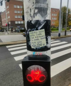 Street sticker A yellow sticky note with a positive affirmation stuck on a pole at a crosswalk. The text on the note reads:
"TODAY... YOU
WILL LOOK
FOR REASONS
TO FEEL GOOD
AND YOU
WILL FIND
THEM"