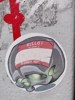 A round sticker featuring a cartoon skull wearing a name tag that says "HELLO! MY NAME IS @gaber_yeat". The skull is gray with glowing green eyes. The name tag is red and white.