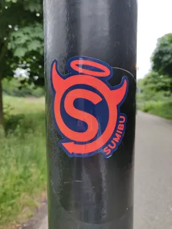A sticker featuring a stylized 'S' logo with devil horns and a halo. The word SUMIBU is written along the bottom curve of the design. The sticker is predominantly red and dark blue, applied to a black pole. 