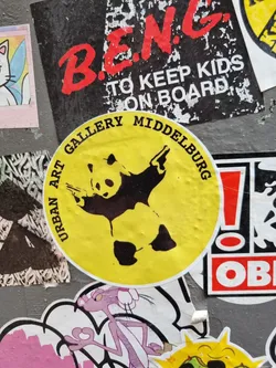 Street sticker Yellow round sticker with a black panda silhouette. The text \"Urban Art Gallery Middelburg\" is written around the circle.