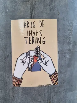 Street sticker A sticker with a drawing of two hands holding a small model of houses and buildings. The text on the sticker says "KRIJG DE INVES TERING" which translates to "Get the investment" in Dutch. The artist's signature is visible at the bottom.