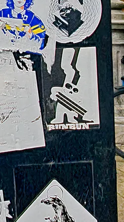 Street sticker The sticker is placed among others on a textured surface. The character is white with black accents and holds the lines horizontally in front of it. The text 'BUNBUN' is printed in a bold font below the character.