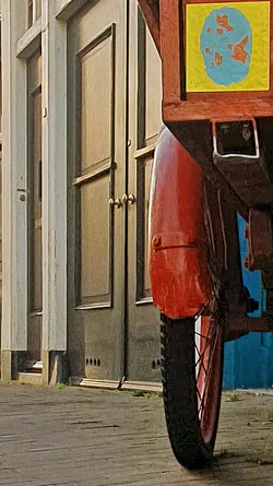 A close-up shot of the rear wheel of a vehicle. A sticker, rendered in yellow with a blue globe-like design on it, is affixed to the vehicle's structure above the wheel.