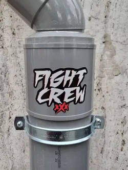Street sticker A sticker with the text "FIGHT CREW" in stylized lettering and two red crosses is affixed to a grey pipe. The sticker appears to be vinyl and is placed near the top of the pipe.