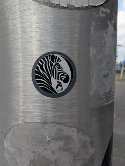 Street sticker A round sticker on a metal pole showing a stylized black-and-white zebra profile. The text 'neofit' is printed in green and black at the bottom. The entire graphic is framed by a dark grey circular border.