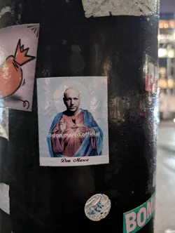 Street sticker A sticker depicting Don Marco in a style reminiscent of religious iconography. The sticker includes the Instagram handle @don_marco.official at the bottom.