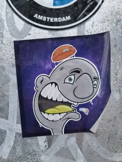 This sticker features a unique cartoon character with an expressive face. The character is drawn in a style that blends elements of street art and illustration. The color palette is primarily purple and grey, with accents of yellow and orange. The character's expression is one of surprise or shock, adding a humorous touch to the design. The background is a deep purple with a cosmic or nebula-like effect.