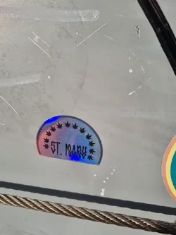 Street sticker A holographic sticker with a semi-circle design featuring marijuana leaves and the text 'ST. MARY' in the center. The sticker has a rainbow effect.