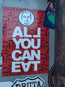 Street sticker A sticker with the text "ALL YOU CAN EAT" in bold white letters on a red background. The background is filled with repeating images of the same man's face. A larger circle version of the man's face is featured at the top. 
