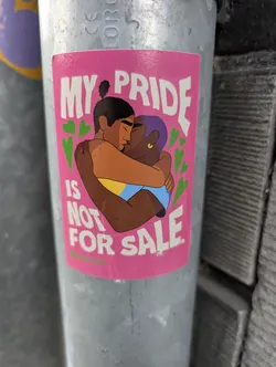 Street sticker A pink rectangular sticker depicting two people of color kissing and hugging, flanked by green hearts. The text 'MY PRIDE IS NOT FOR SALE.' is written in bold white letters. A small green Oxfam Novib logo is at the bottom left.