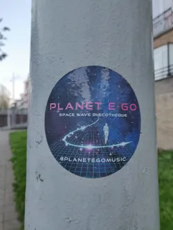Street sticker Round sticker featuring a cosmic design, a person walking on a glowing path, and grid-like background.  Text includes 'PLANET E-GO' and 'SPACE WAVE DISCOTHEQUE'. A social media handle is visible at the bottom.