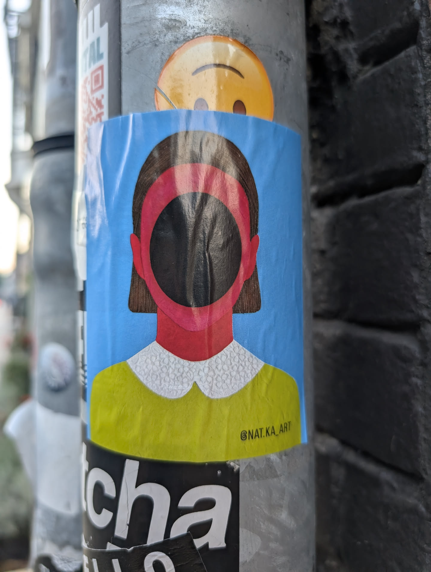 A rectangular sticker depicting a stylized, faceless figure with brown hair against a blue background. The face is a black circular void ringed in pink. The figure wears a yellow top with a white patterned collar. The text '@NAT.KA_ART' is in the bottom right corner.