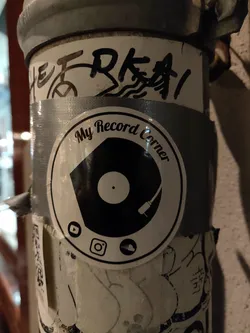 Street sticker A black and white sticker featuring a vinyl record and turntable.  It includes social media icons for YouTube, Instagram, and a cloud storage service.  The text 'My Record Corner' is visible.