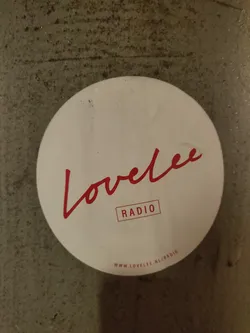 Street sticker Round white sticker with red text.  The main text says "Lovelee" in a stylized script font, with the word "RADIO" underneath in a sans-serif font.  A URL is printed at the bottom.