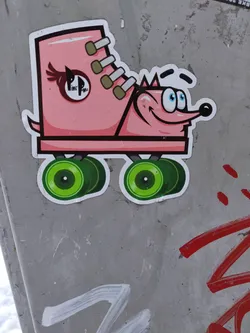 A pink roller skate with a cute critter face. The skate has green wheels and laces. There is a logo on the side of the skate that says Pink Panther.