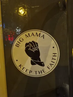 Street sticker A round sticker with a black and white design. It features two hands clasped together in prayer, with a cross on one wrist. The text "Big Mama" is written at the top and "Keep the Faith" at the bottom.