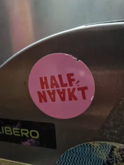 Street sticker Pink round sticker with the text "HALF-NAAKT" in red. The sticker is slightly damaged.