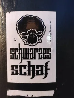 Street sticker A sticker featuring a cartoon black sheep with an afro and the text "Schwarzes Schaf" in a stylized gothic font.  A website address is also present at the top right corner.