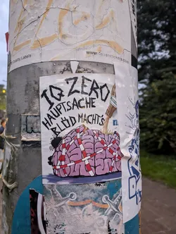 Street sticker A sticker featuring a cartoon brain wrapped in red and white tape, with the text "IQ ZERO HAUPTSACHE BLÖD MACHT'S".  The style is dark humor, possibly punk or anti-establishment.