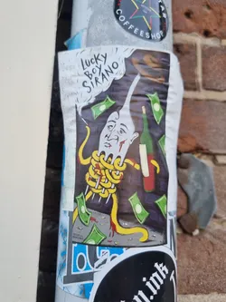 Street sticker A colorful sticker featuring a cartoon illustration of a man's head entangled in spaghetti, with money falling around him.  A wine bottle is also present. The words "Lucky Boy Sirano" are written in the top left corner of the sticker.