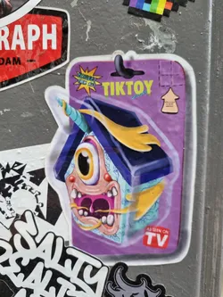 Street sticker A vibrant sticker featuring a cartoon monster house character, part of the TikToy collectible series. The sticker has a purple background with yellow and blue accents, and a small tag indicating it's been seen on TV.
