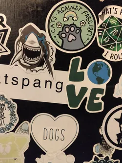 Street sticker A sticker of a great white shark with its mouth open, showing sharp teeth.  The style is somewhat cartoonish but still captures the intensity of the animal. The shark is centered on the sticker, with some jagged edges around it implying movement or water. 