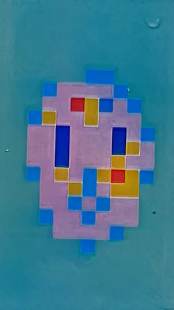 Street sticker The sticker features a pixelated design reminiscent of a Space Invader, rendered in shades of light purple, blue, red, and yellow. It has a geometric, retro aesthetic, with a simple and stylized shape.