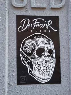 Street sticker Black and white sticker featuring a skull wearing a facemask. The sticker has Dr. Frank Tattoo written at the top and an Instagram logo at the bottom.