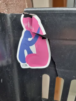 Street sticker This sticker depicts a simple, stylized illustration of two figures, one blue and one pink, in a tender embrace. The style is minimalist and modern. The sticker itself is damaged, with a significant tear along the right side, revealing the surface beneath. Despite the damage, the central image remains largely intact.  A small text, 'VICON.', appears at the bottom of the design.