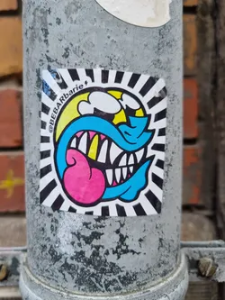 Street sticker This sticker features a vibrant cartoon character with a playful expression, characterized by its big teeth and bright colors. The style is reminiscent of pop art and street art.