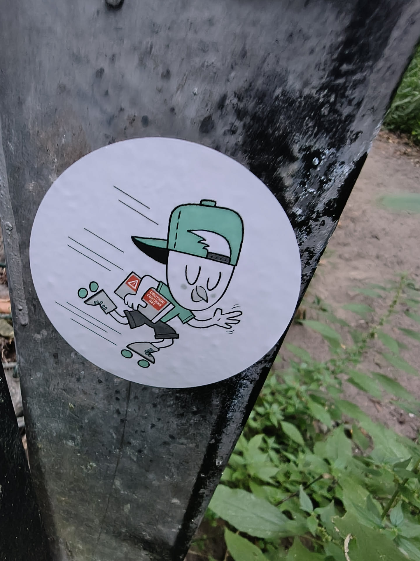 Circular white sticker depicting a cartoon character roller-skating at high speed. The character wears a green backwards cap, green shirt, and skates, while carrying a package labeled 'CAUTION CONTAINS ART'.